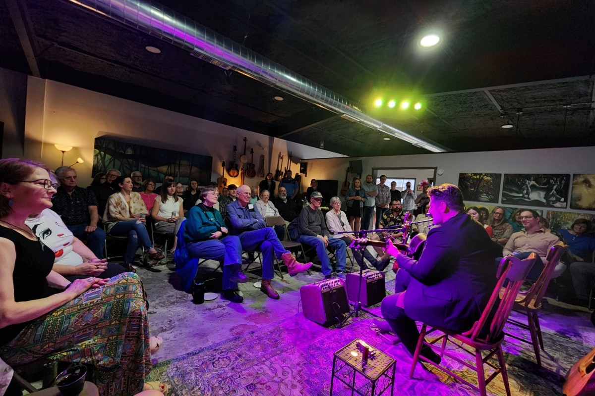 Musicians perform in a small, dimly lit art studio.