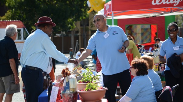 Two men shaking hands while attending an outdoor community event.